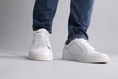 Photo of Man wearing stylish white sneakers on grey background, closeup