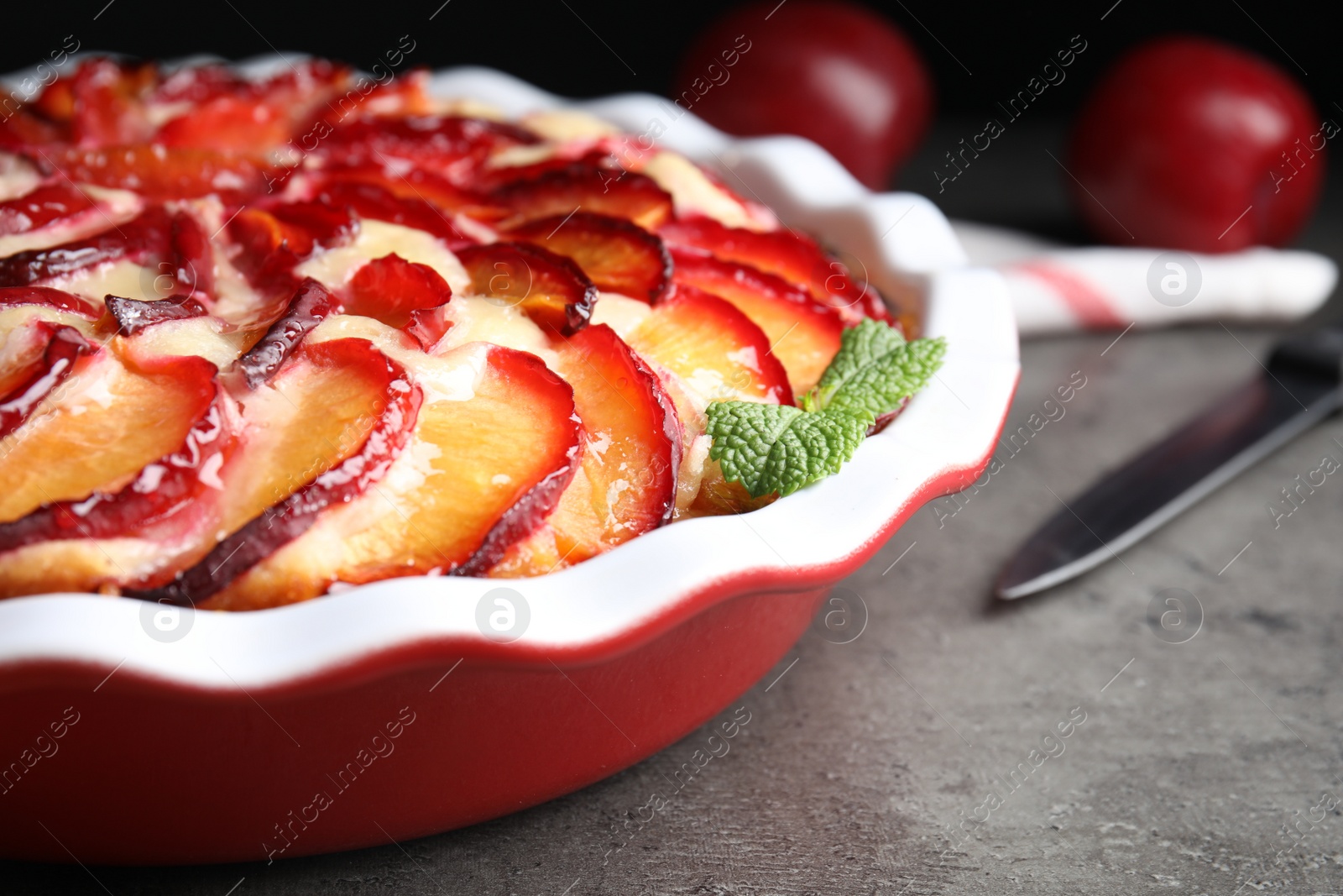 Photo of Delicious cake with plums on grey table, closeup