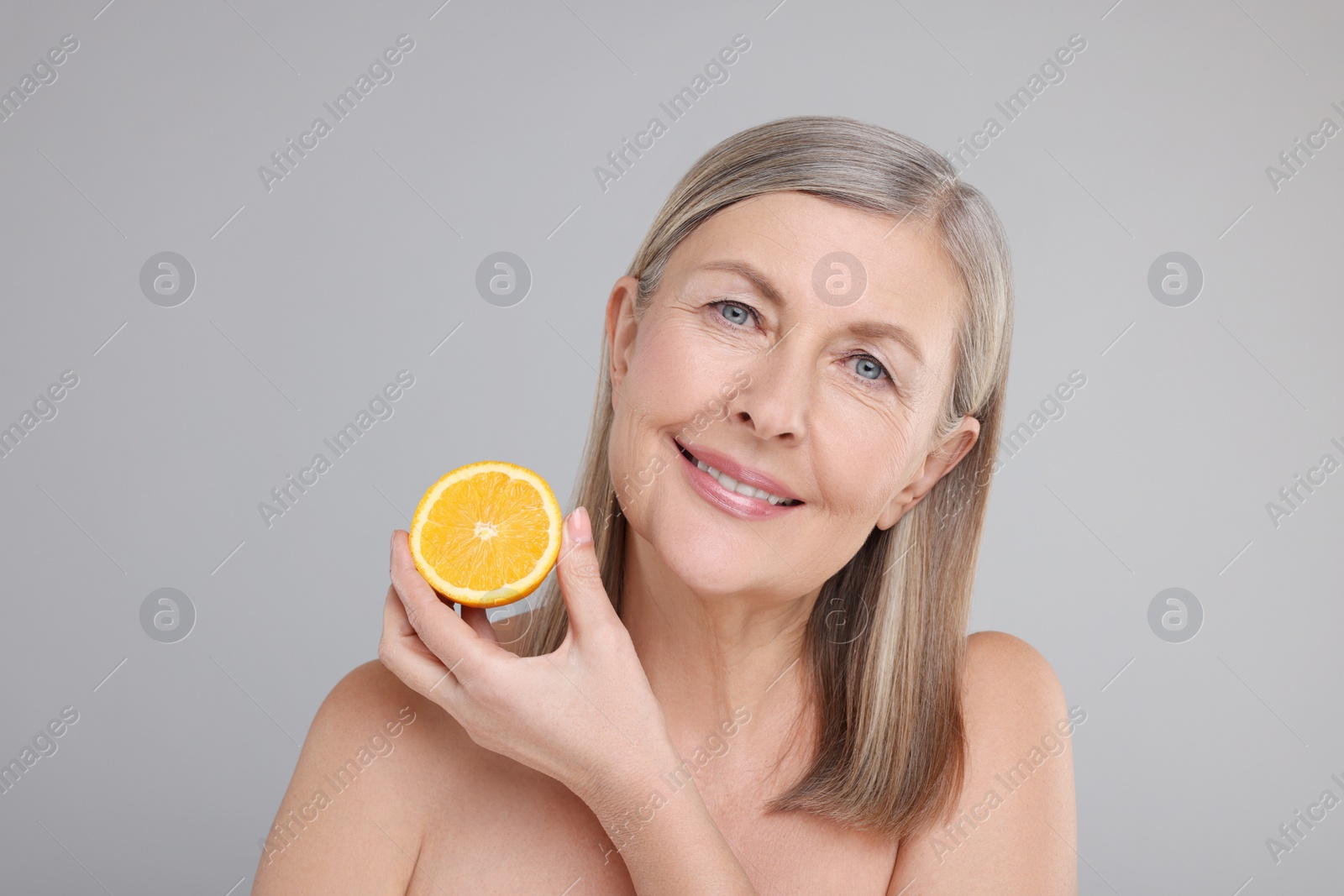 Photo of Beautiful woman with half of orange rich in vitamin C on grey background