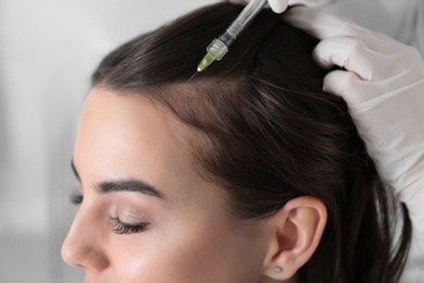 Photo of Young woman with hair loss problem receiving injection in salon, closeup