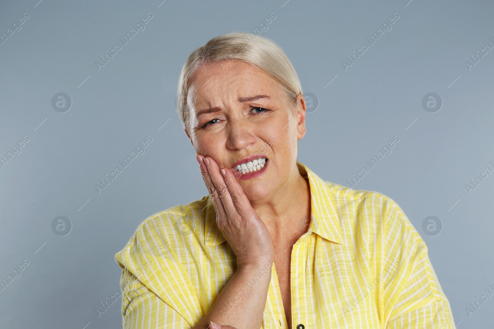 Image of Mature woman suffering from toothache on grey background