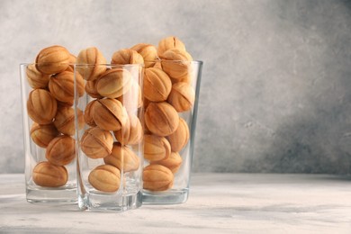 Photo of Tasty walnut shaped cookies served in glasses for welcoming guests on light grey table, space for text. Homemade pastry with caramelized condensed milk filling
