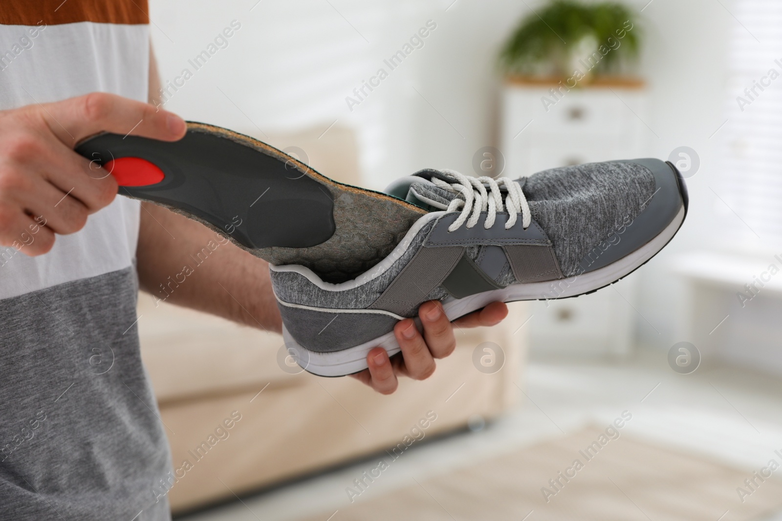 Photo of Man putting orthopedic insole into shoe at home, closeup