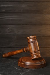 Photo of Wooden gavel on dark textured table. Space for text