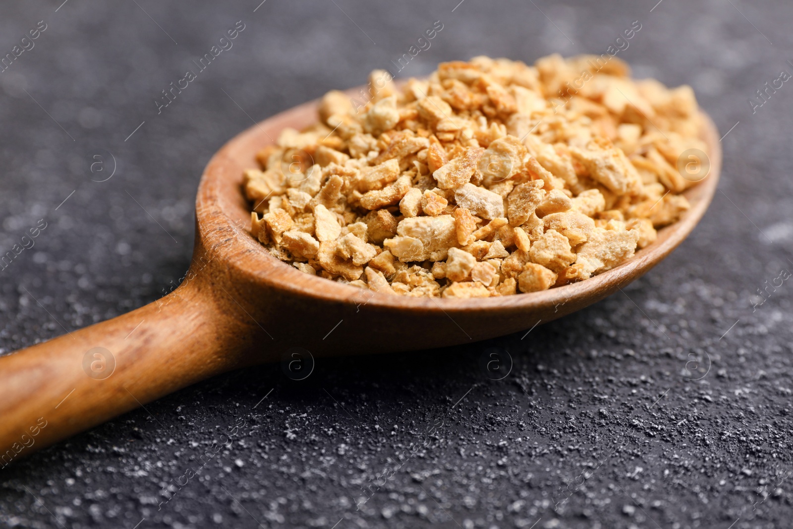 Photo of Spoon with dried orange zest seasoning on grey table, closeup
