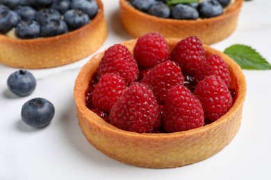 Photo of Tartlet with fresh raspberries on white table, closeup. Delicious dessert