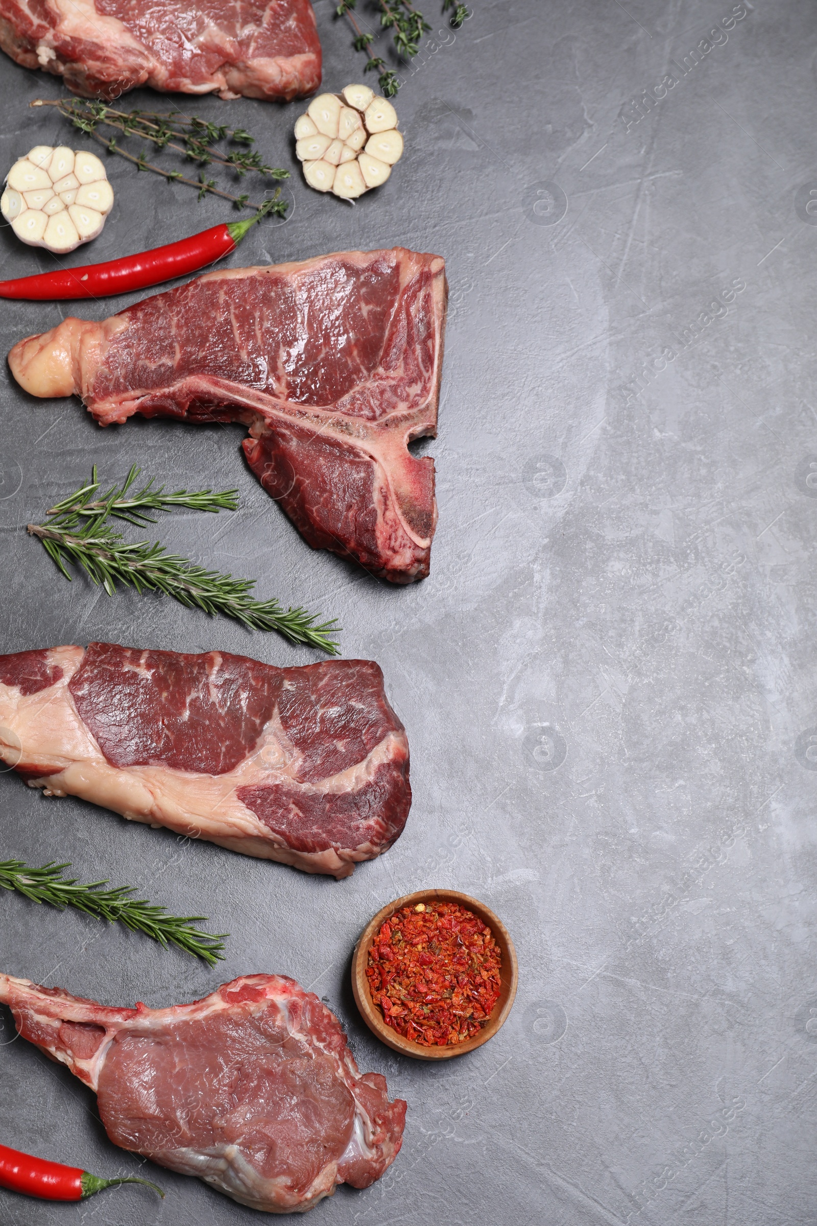 Photo of Fresh raw beef cuts and different spices on light grey textured table, flat lay. Space for text