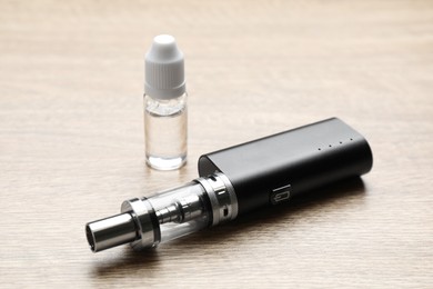 Photo of Electronic cigarette and vaping liquid on wooden table. Smoking alternative