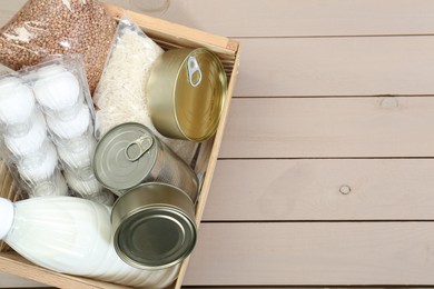 Photo of Donation box with food products on wooden table, top view. Space for text