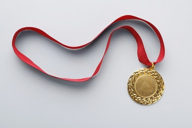 Photo of Gold medal with space for design on light background, top view. Victory concept