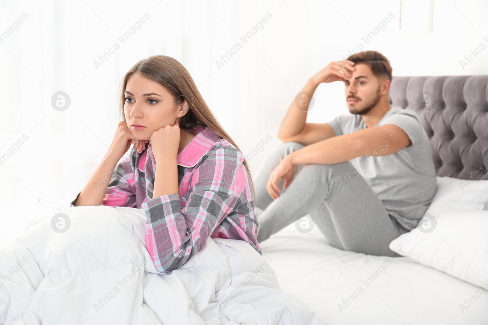 Photo of Young couple with relationship problems ignoring each other in bedroom