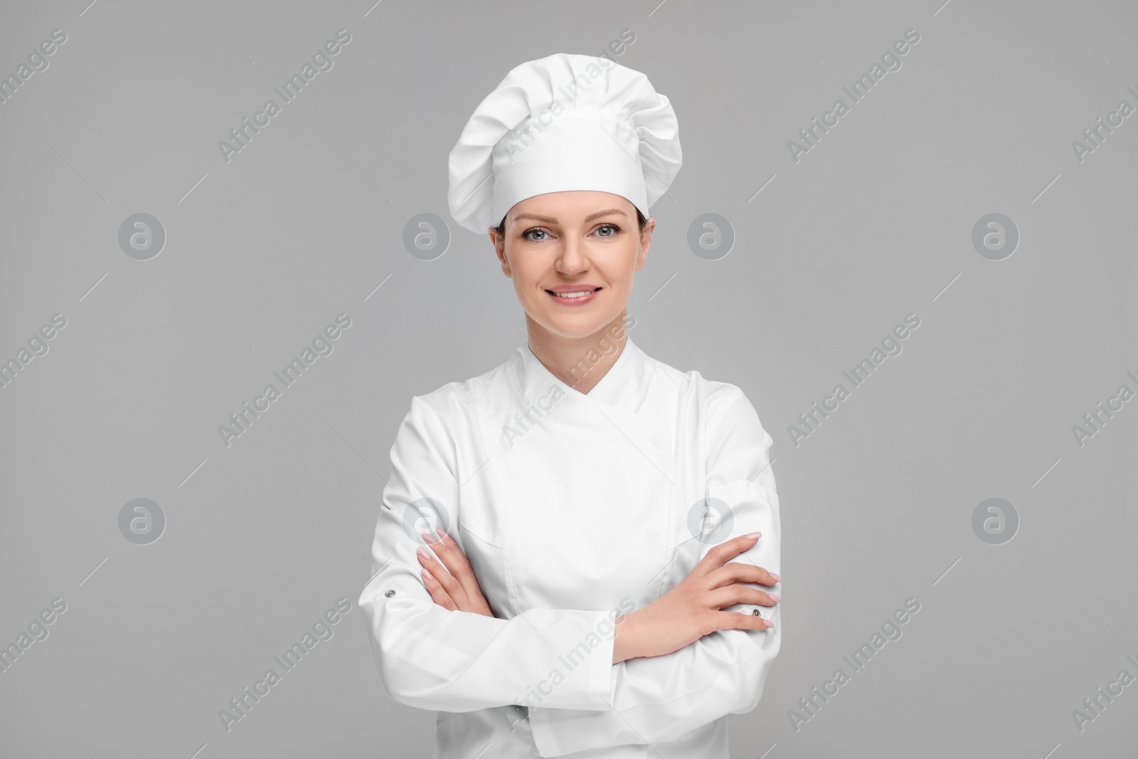 Photo of Happy chef in uniform on grey background