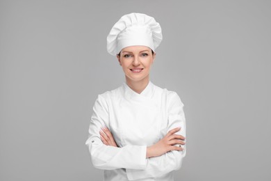 Photo of Happy chef in uniform on grey background