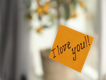 Sticky note with handwritten text I Love you attached to mirror in room, closeup. Romantic message