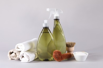 Bottles of cleaning product, brushes, rags and baking soda on light background