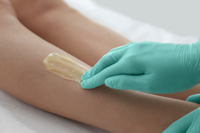 Photo of Woman getting wax epilation of legs in salon, closeup