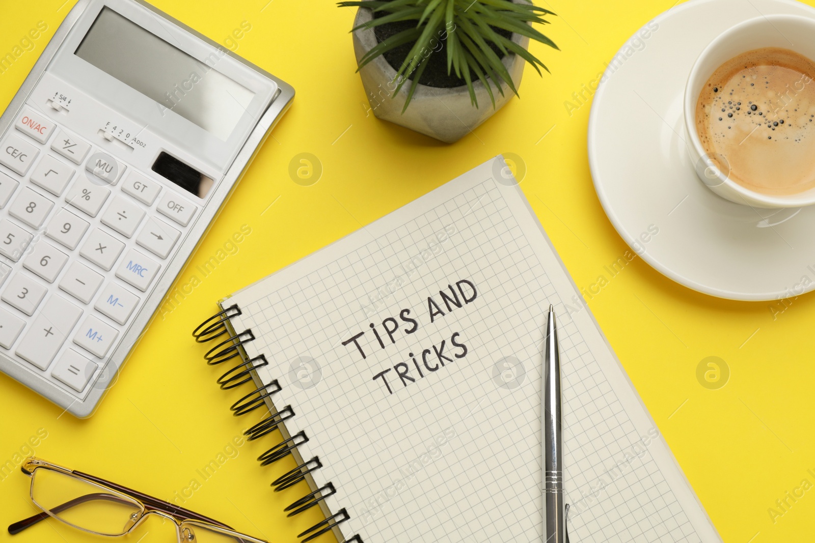 Photo of Flat lay composition with phrase Travel Tips written in notebook, cup of coffee, calculator and plant on yellow background