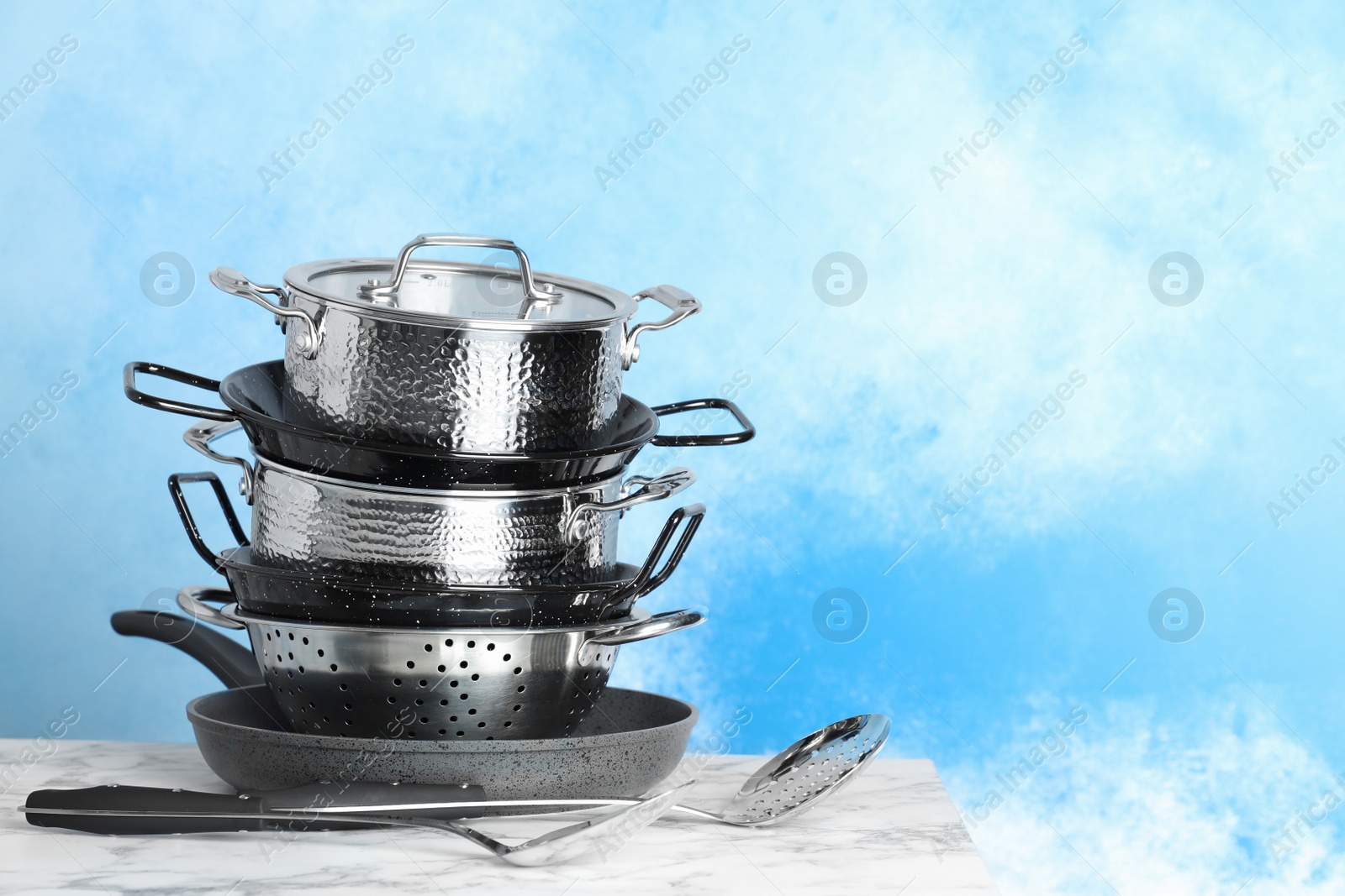 Photo of Set of clean cookware and utensils on table against color background. Space for text