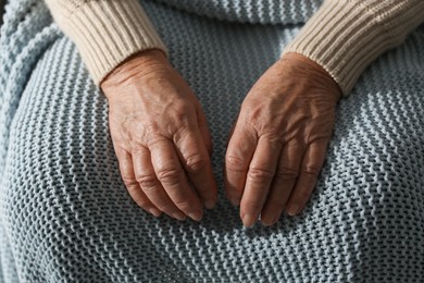 Photo of Elderly woman with grey knitted blanket, closeup