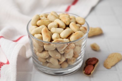 Roasted peanuts in bowl on white table, closeup