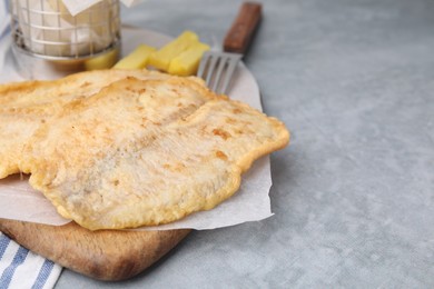 Photo of Delicious fish and chips served on gray table, closeup