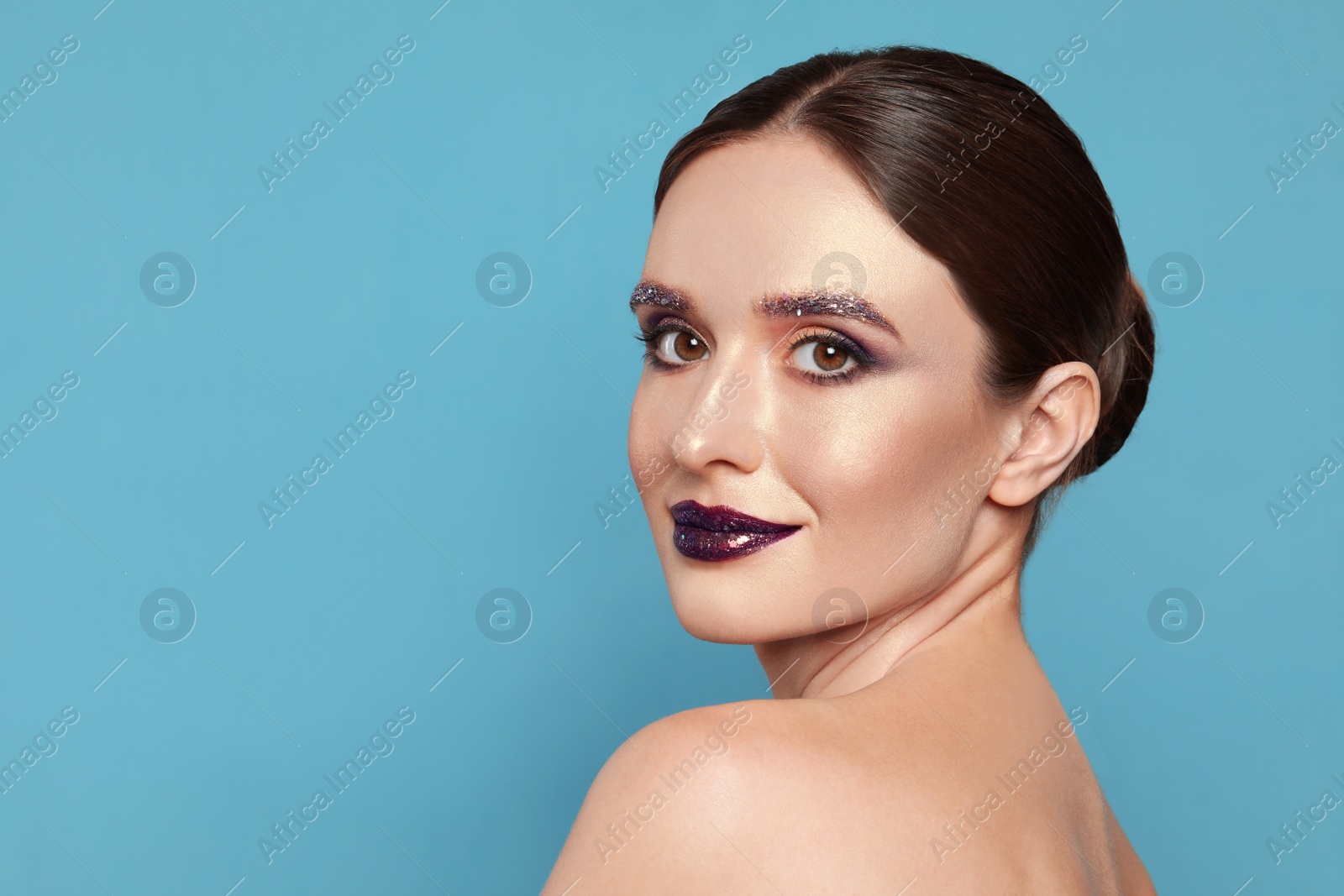 Photo of Beautiful young woman with glitter makeup on blue background, space for text