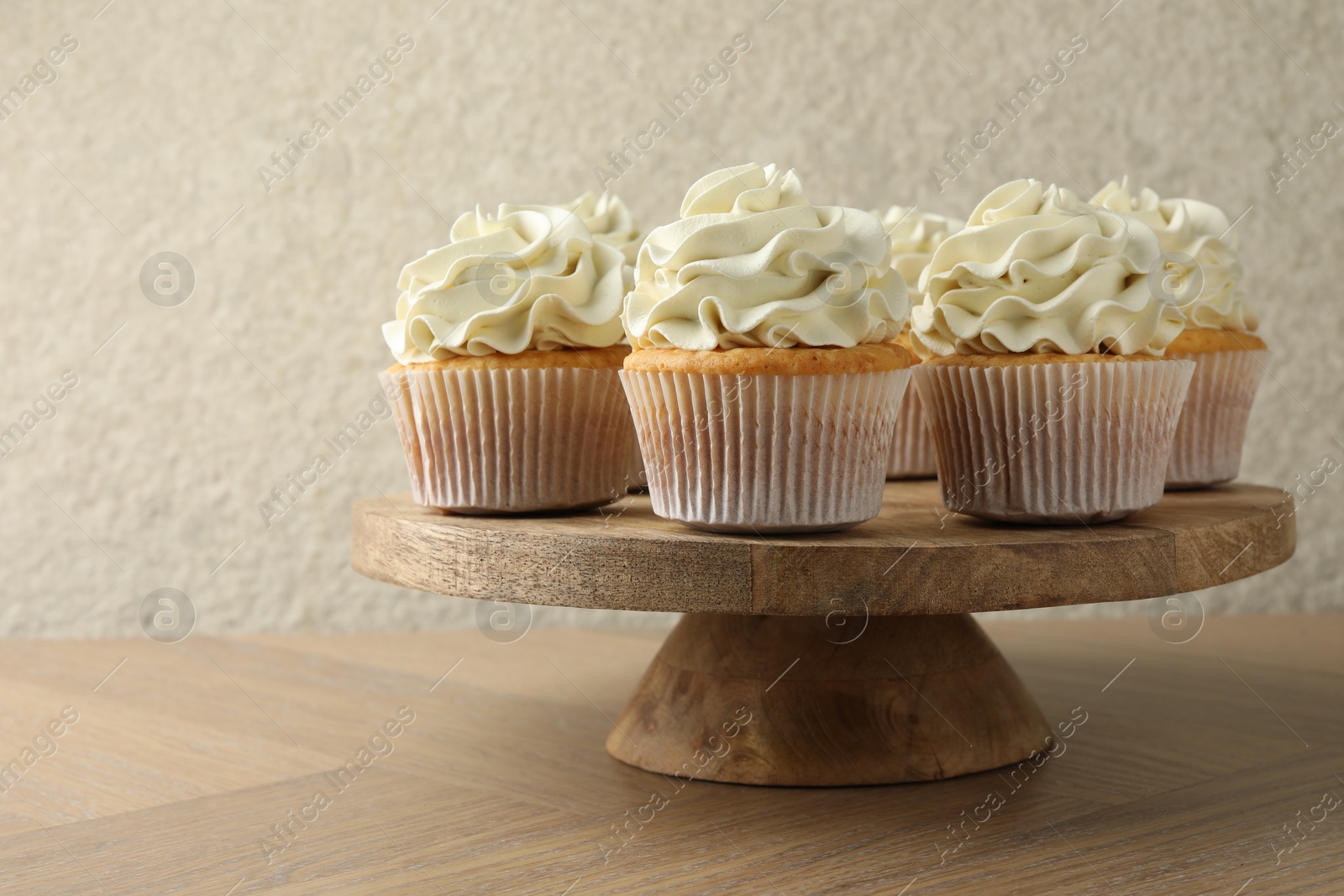 Photo of Tasty vanilla cupcakes with cream on wooden table