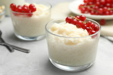 Photo of Delicious rice pudding with redcurrant on marble table, closeup