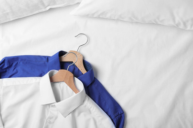 Stylish shirts on bed, top view. Dry-cleaning service