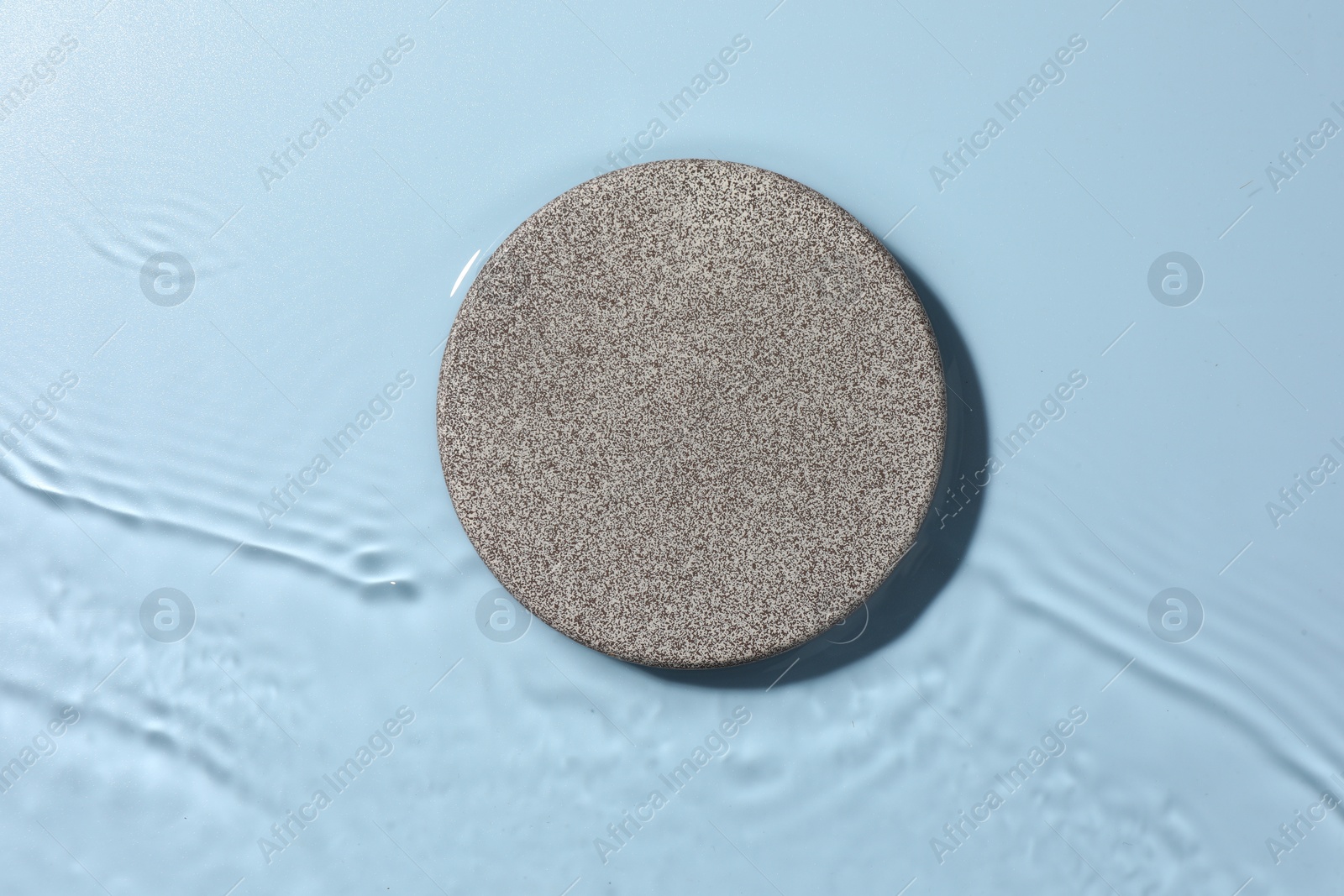 Photo of Presentation for product. Stone podium in water on light blue background, top view