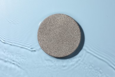 Photo of Presentation for product. Stone podium in water on light blue background, top view