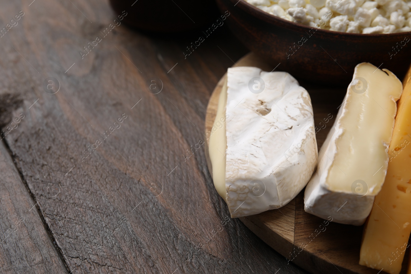 Photo of Dairy products. Different kinds of cheese on wooden table, closeup. Space for text