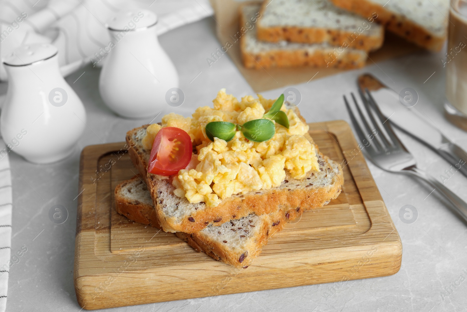 Photo of Tasty scrambled egg sandwich on wooden board