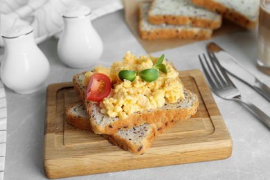 Tasty scrambled egg sandwich on wooden board
