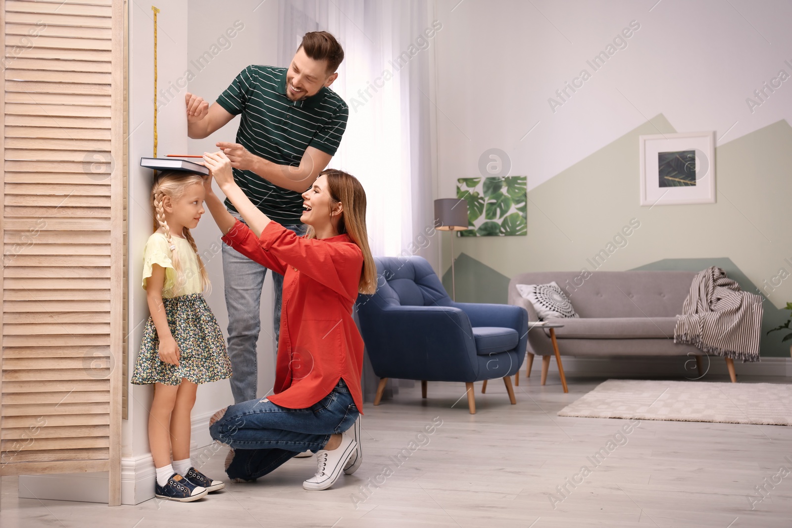 Photo of Parents measuring their daughter's height at home