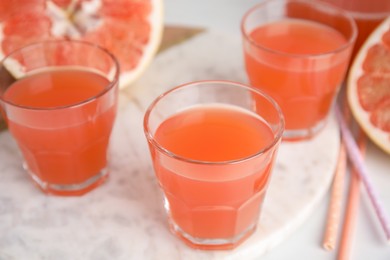 Photo of Glasses of pink pomelo juice on white table, closeup