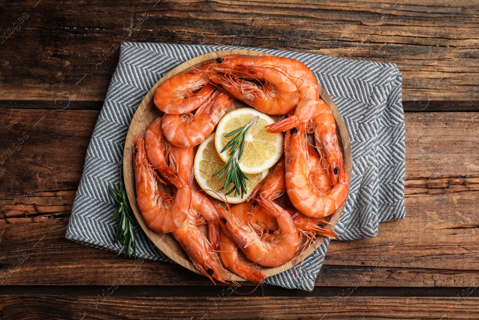 Photo of Delicious cooked shrimps with rosemary and lemon on wooden table, top view