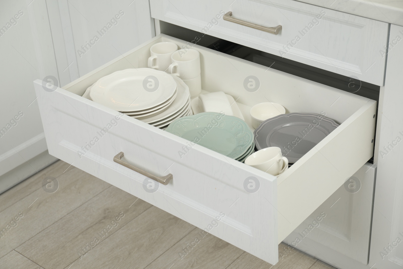 Photo of Clean plates, cups and bowl in drawer indoors