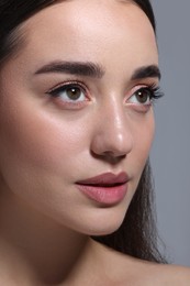 Portrait of beautiful young woman on grey background, closeup