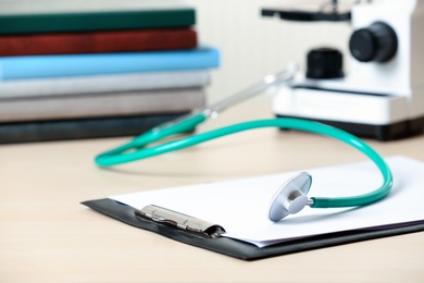 Photo of Clipboard with report and stethoscope on table. Medical students stuff
