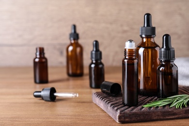 Bottles of rosemary essential oil on wooden table. Space for text