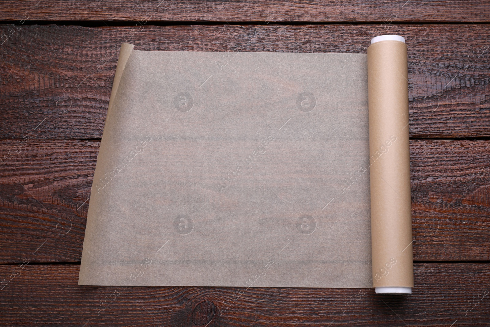 Photo of Roll of baking paper on wooden table, top view