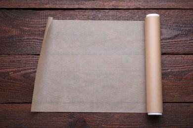 Roll of baking paper on wooden table, top view