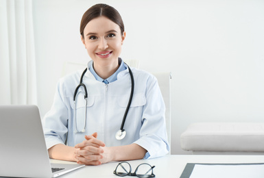 Portrait of young female doctor in white coat at workplace