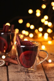 Photo of Glass cup with mulled wine on table against blurred background