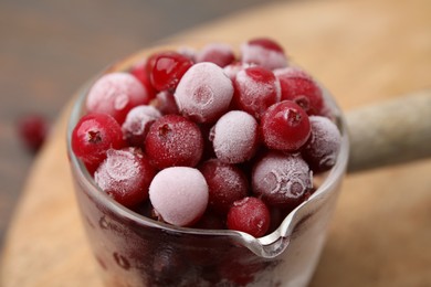 Photo of Frozen red cranberries in glass pot on table, closeup