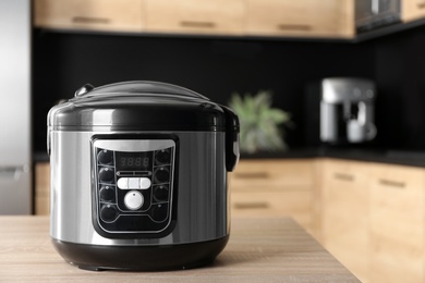 Modern multi cooker on table in kitchen, space for text