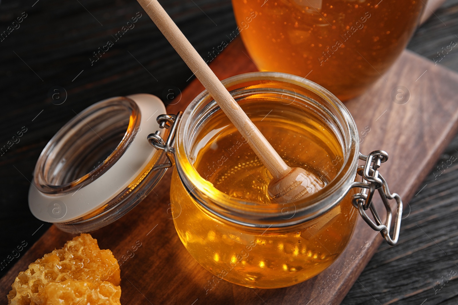 Photo of Jar of sweet honey on wooden board