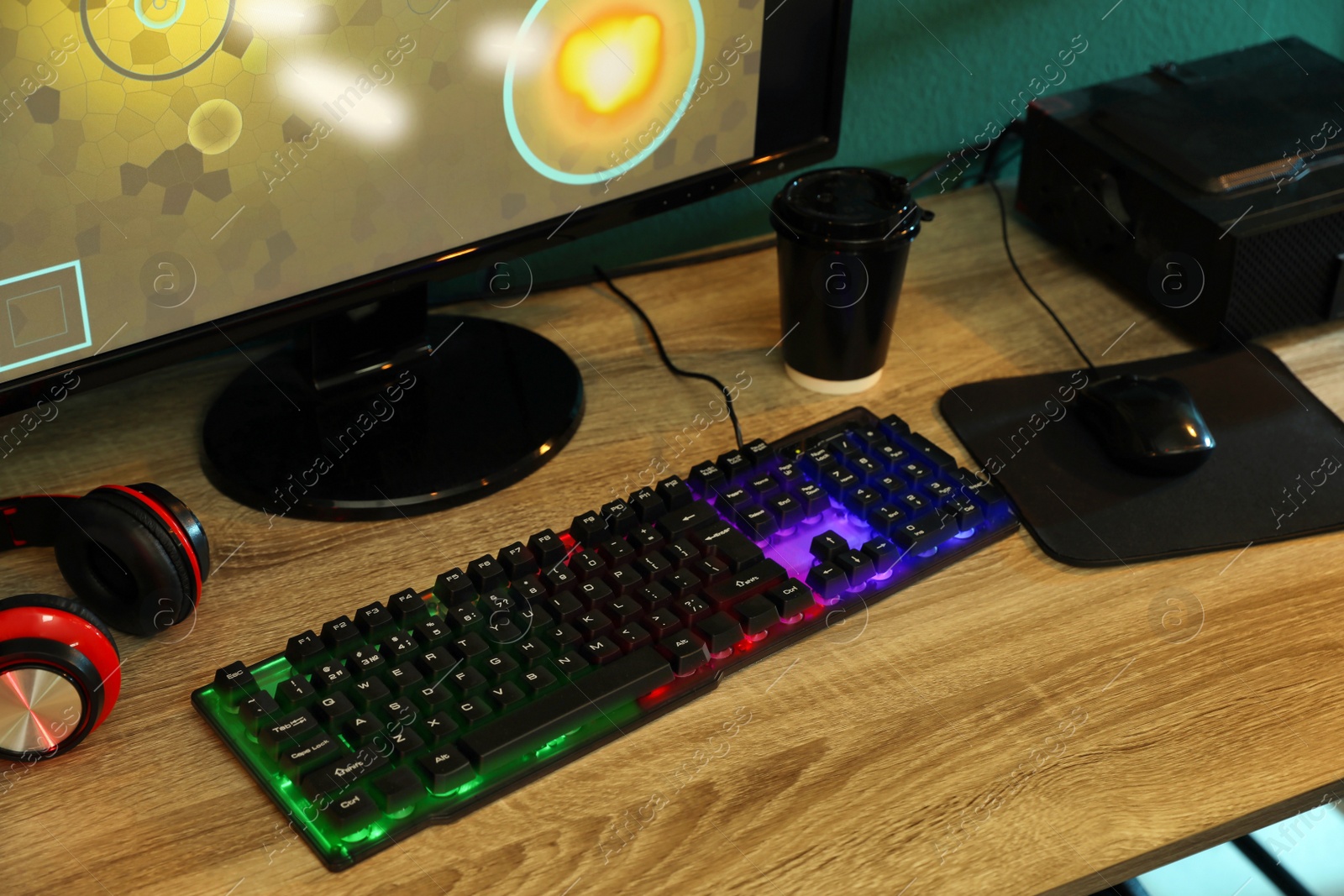 Photo of Modern RGB keyboard, computer and headphones on wooden table indoors