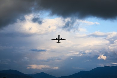 Photo of Modern white airplane flying in sky with clouds, low angle view